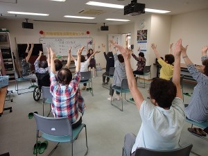 介護予防教室の風景です。両手を大きく上げて体を伸ばします。